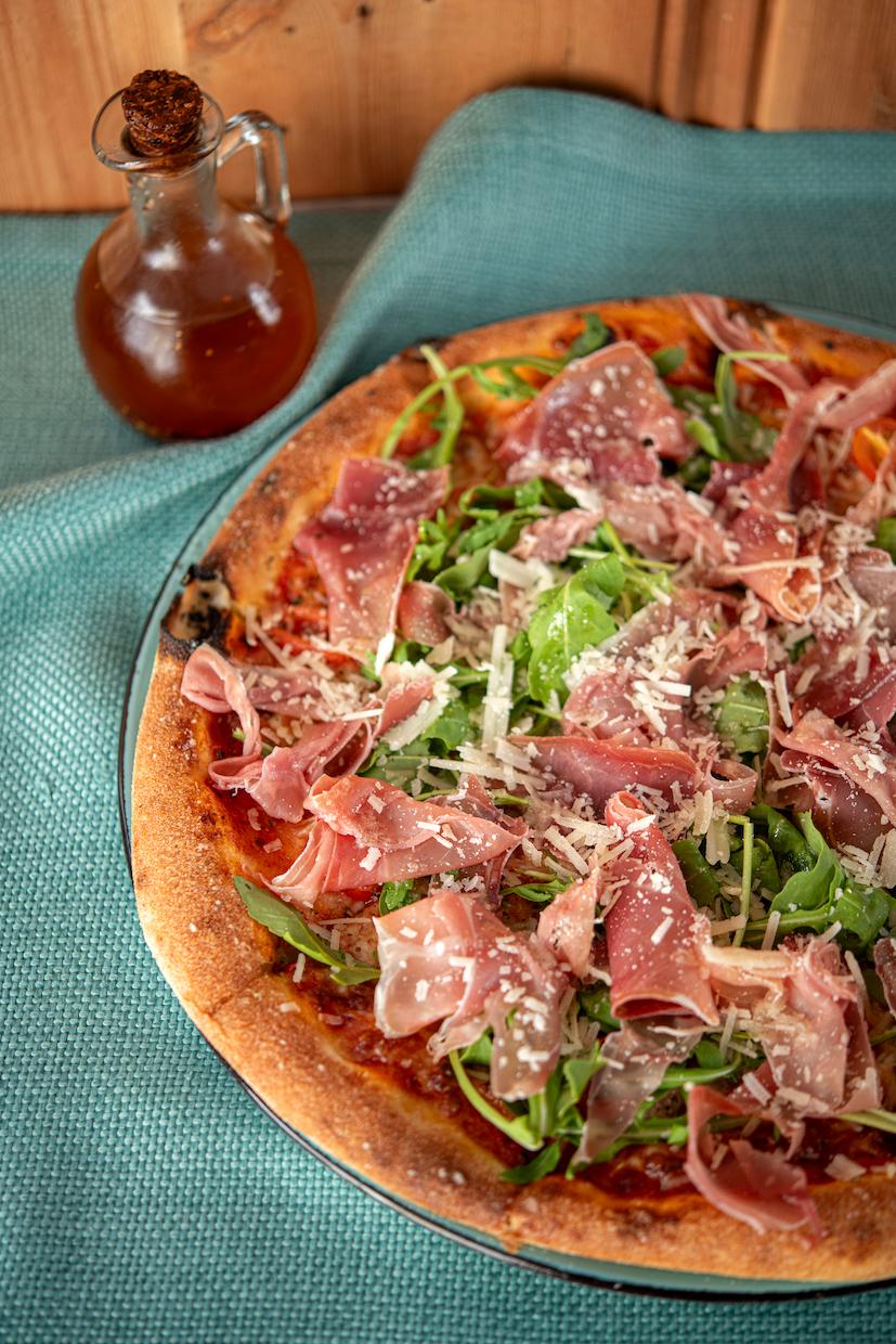 Pizza z szynką dojrzewającą, rukolą i płatkami sera w restauracji California